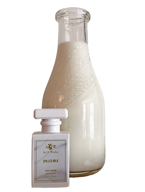 Air & Weather's Spilled Milk Perfume, 1 oz. bottle sits beside a tall old fashioned glass milk bottle filled with milk.